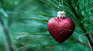 Red glitter heart ornament hanging on pine