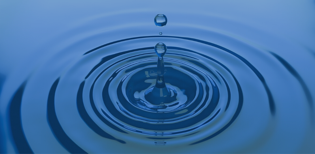 Blue water droplet creating concentric ripples